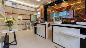 A reception area with marble counters, a digital screen, and informational posters on the wall. - Shenzhen Qiaonan Hotel (Shenzhen)