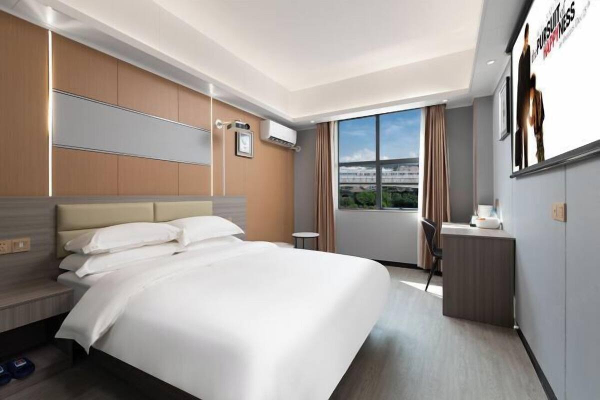 Quarto de hotel com uma cama grande, uma escrivaninha e vista para a paisagem urbana.