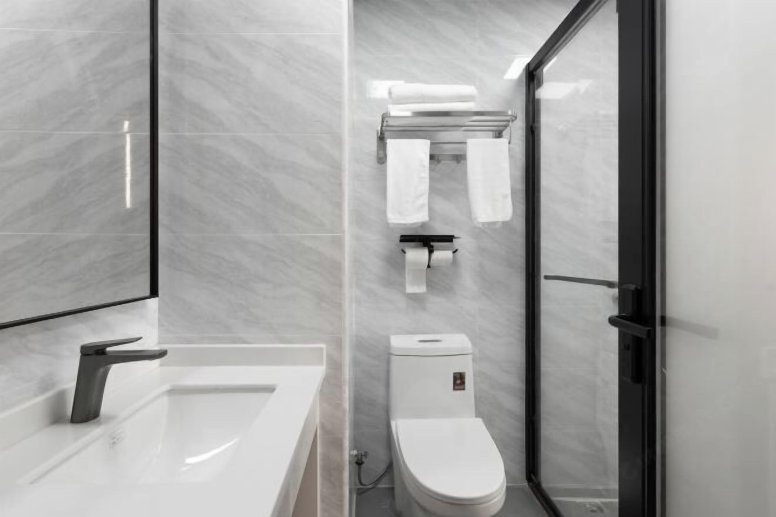 A modern bathroom with a white sink, toilet, and glass shower enclosure.