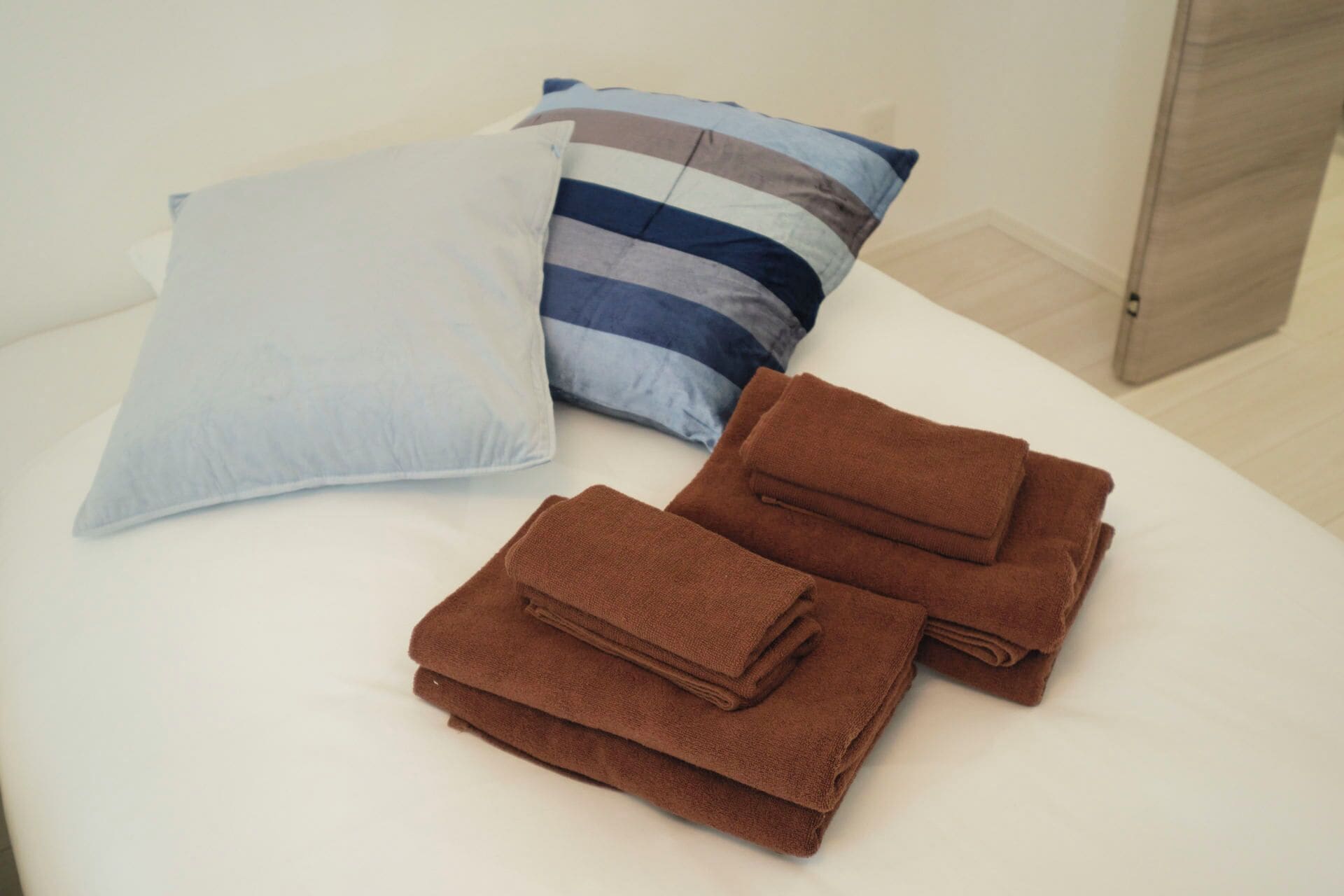 A bed with two pillows and folded towels.