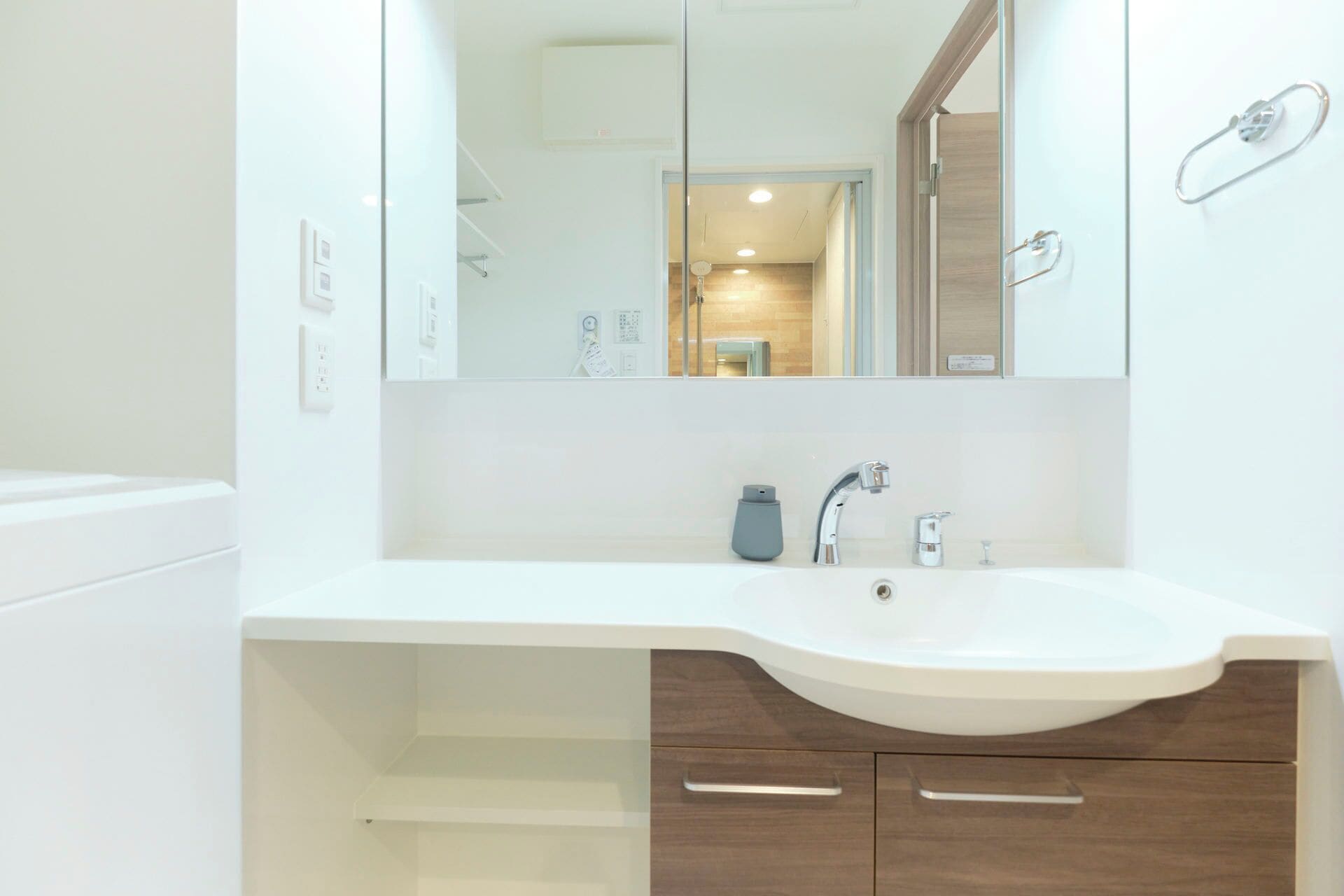 A modern bathroom with a white sink, a mirror, and wooden cabinets.