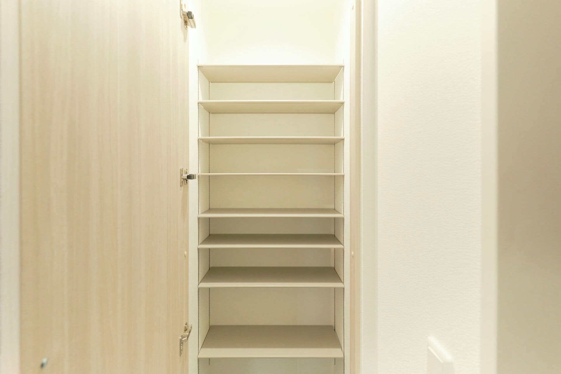 Un couloir étroit, avec une porte en bois sur la gauche et un mur blanc sur la droite.