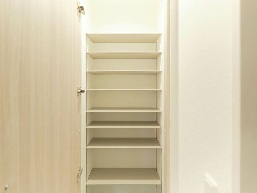 Un couloir étroit, avec une porte en bois sur la gauche et un mur blanc sur la droite.