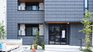 A modern building with a textured facade, large windows, and a gated entrance. - Grand Grace Zoshiki by Tranova (Tokyo)