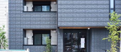 A modern building with a textured facade, large windows, and a gated entrance.