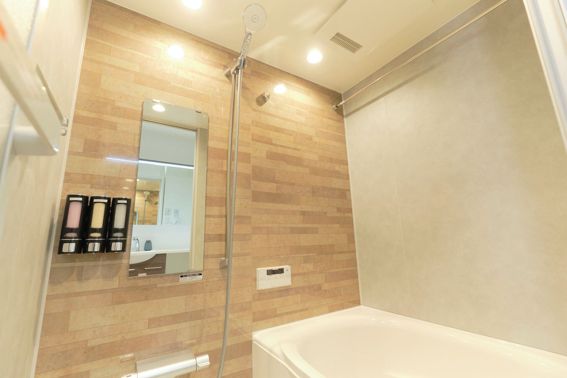 Ein modernes Badezimmer mit Duschkabine aus Glas, einer weißen Badewanne und einem Spiegel mit Holzvertäfelung.