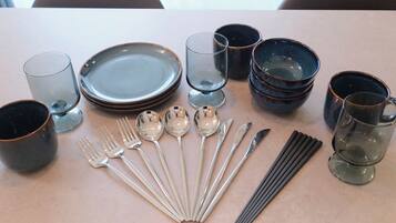 A table set with plates, bowls, cups, spoons, forks, and chopsticks.