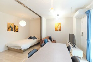 A modern bedroom with a bed, a sofa, a TV, and artwork on the walls. - Grand Grace Zoshiki by Tranova (Tokyo)