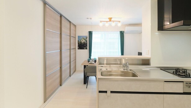 A modern kitchen with a central island, a built-in stove, and a large window with curtains. - Grand Grace Zoshiki by Tranova (Tokyo)