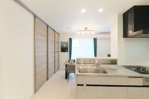 A modern kitchen with a central island, a built-in stove, and a large window with curtains. - Grand Grace Zoshiki by Tranova (Tokyo)