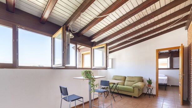 A spacious room with a high ceiling, large windows, a green sofa, two chairs, and a small table. - Ático Playa Zapillo by Interhome (Almería)