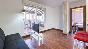 A spacious room with a large window, a white desk with a computer, a black sofa, and a red chair. - Ático Playa Zapillo by Interhome (Almería)