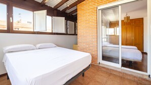 A bedroom with a bed, a sliding glass door to a balcony, and a brick wall. - Ático Playa Zapillo by Interhome (Almería)