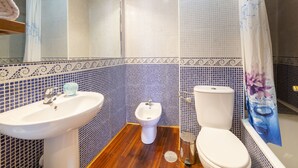 A bathroom with a sink, toilet, and bidet. The walls are tiled with a blue and white pattern. - Ático Playa Zapillo by Interhome (Almería)