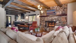 A spacious living room with a stone fireplace, a leather armchair, and a large sofa. - Modern Retro Tahoe Chic Chalet (Tahoe City)