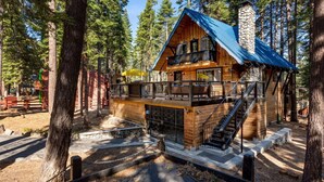 A cabin with a wooden exterior, a stone chimney, and a balcony with a metal railing. - Modern Retro Tahoe Chic Chalet (Tahoe City)
