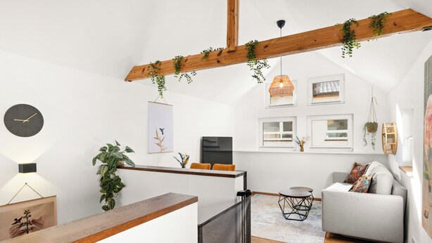 En modern inredning med ett träpanelat tak, en soffa, ett skrivbord och en klocka.