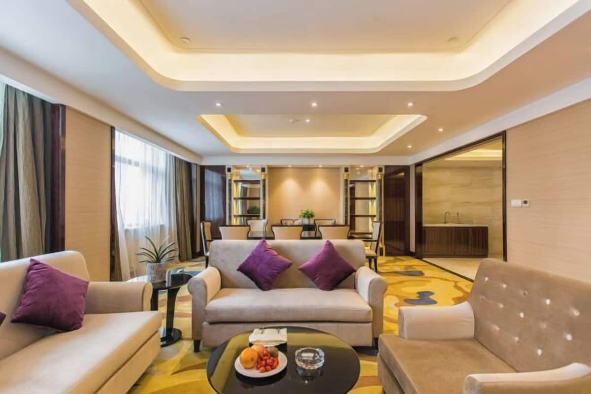 Habitació d'hotel moderna amb seients de sofà, una taula de cafè amb fruita i una estanteria.
