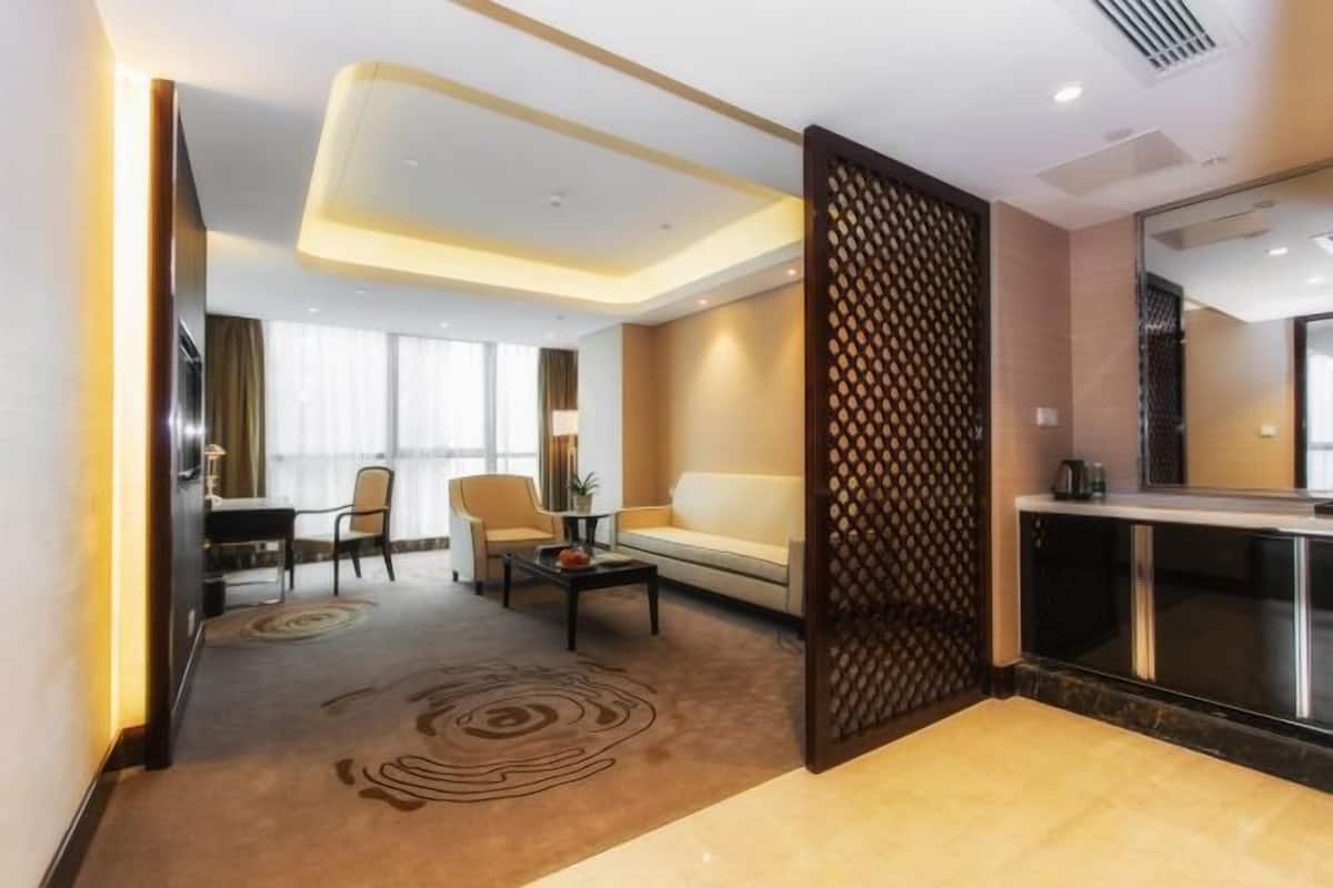 Habitació d'hotel moderna amb sofà, taula de dinar i un separador decoratiu.