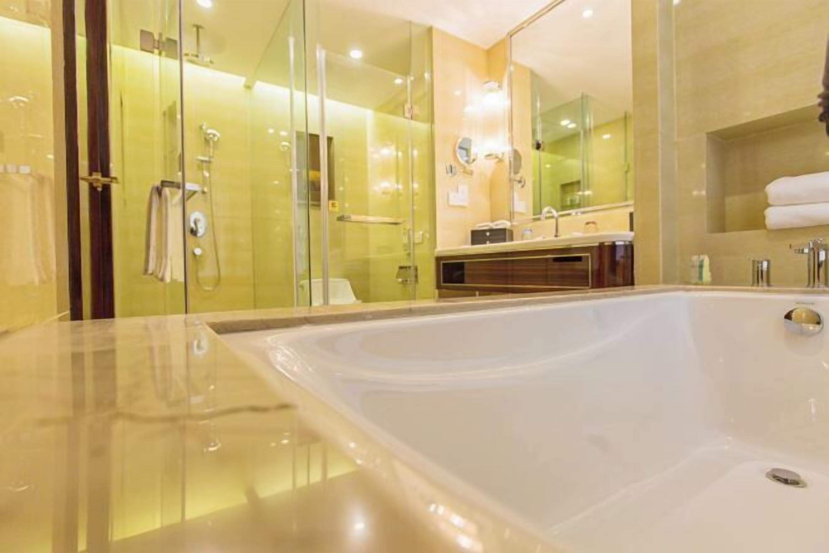 A modern bathroom with a large bathtub, glass shower enclosure, and a vanity with a mirror.