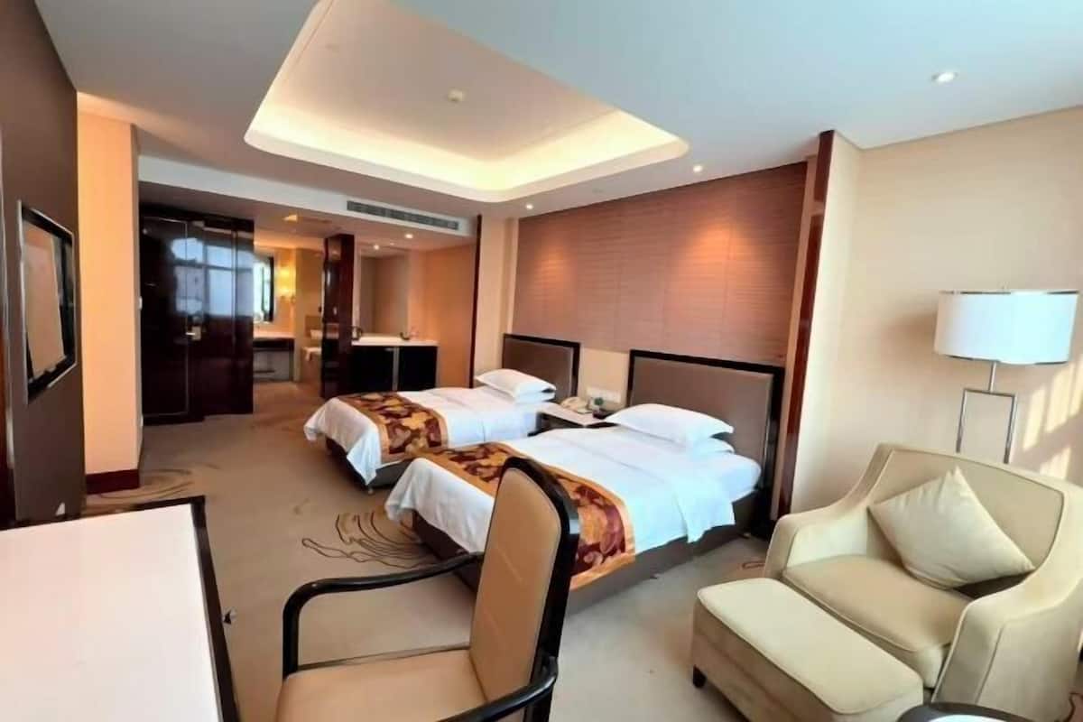 Habitació d'hotel amb dos llits, un sofà, una cadira i un escriptori.