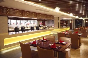 Un restaurante moderno con una barra larga, varias mesas y una zona de bar.