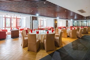 Un comedor amplio con mesas y sillas redondas, ventanas grandes y un diseño de techo moderno.