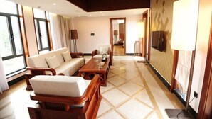 Una habitación de hotel amplia con un sofá grande, una mesa de centro de madera y un televisor montado en la pared.