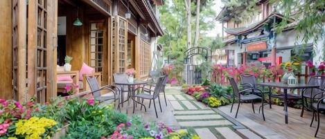 Un patio con edificios de madera, mobiliario exterior y una variedad de flores.