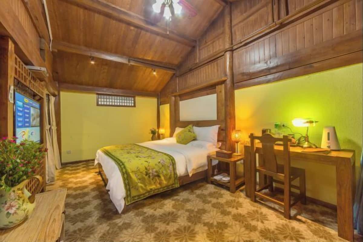 A cozy room with a bed, bedside table, lamp, chair, and a small desk with a computer.