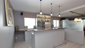 Een moderne keuken met een centraal eiland, hangende lampen en een inbouwbar met flessen en glazen.