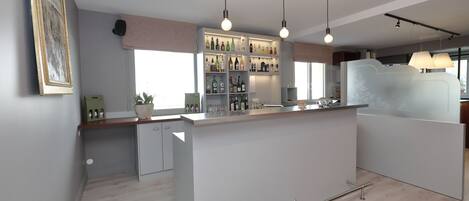Eine moderne Küche mit einer zentralen Kochinsel, Pendelleuchten und einer integrierten Bar mit Regalen voller Flaschen und Gläsern.