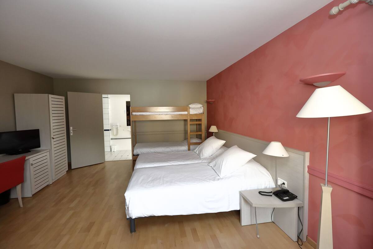 Une chambre d’hôtel avec deux lits, un bureau avec une lampe, une télévision et un téléphone.