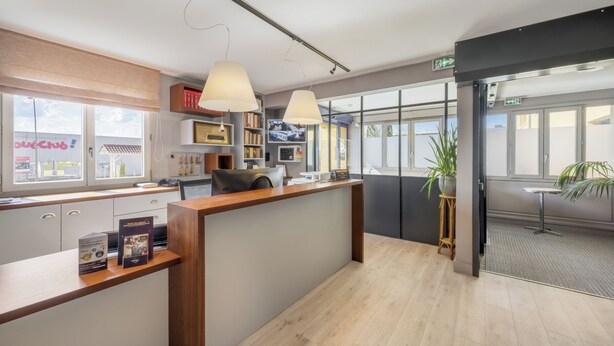 Een moderne receptie met een houten balie, een groot raam en een potplant.