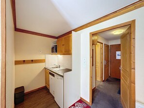 Kitchen area with microwave, dishwasher, and sink, set against a tiled backsplash and wooden floor.