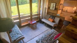 A cozy cabin interior with a sofa, a small table, and a kitchen area.