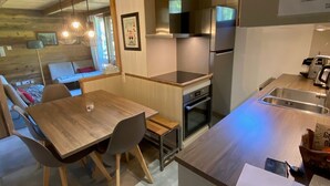 A modern kitchen with a wooden dining table, chairs, and a built-in oven.