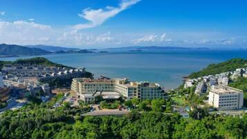 A coastal resort with multiple buildings, a large body of water, and a mountainous backdrop.