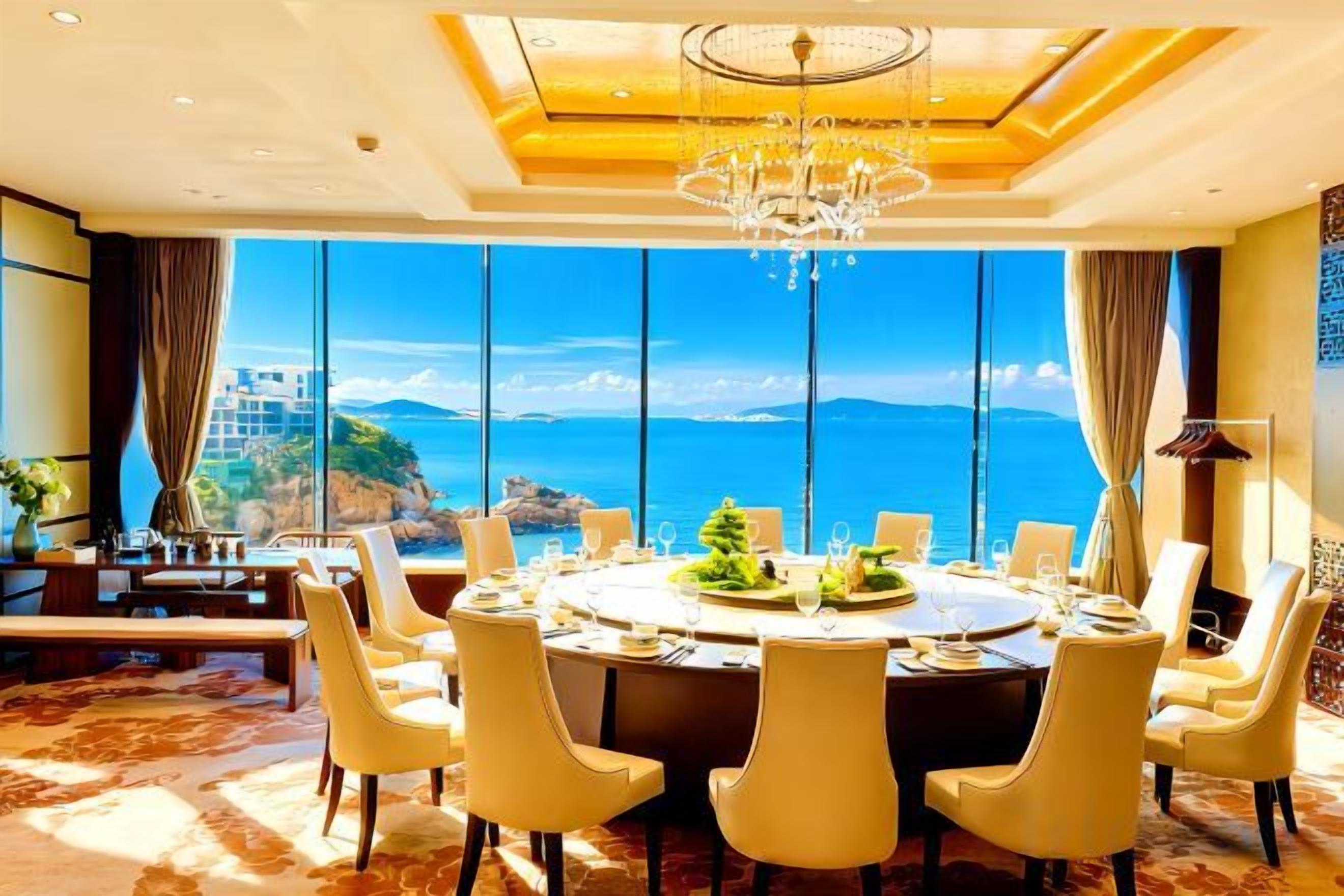 A dining area with a large round table, multiple chairs, and a view of the ocean.