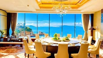 A dining area with a large round table, multiple chairs, and a view of the ocean.