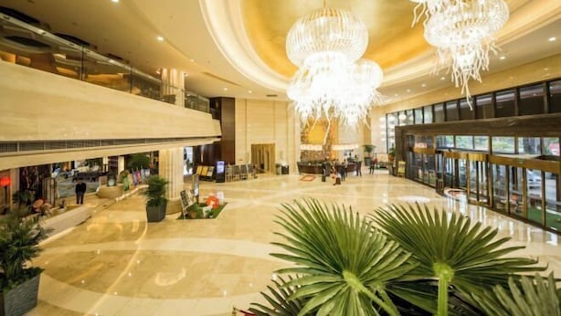Un vestíbulo espacioso con un alto techo, varios candelabros y una zona de estar central.