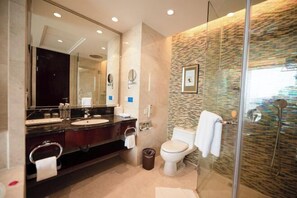 A modern bathroom with a large mirror, dual sinks, a toilet, and a glass-enclosed shower. - Grand New Century Resort Dongtou Wenzhou (Wenzhou)