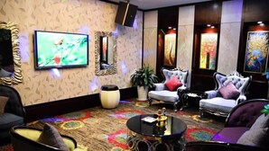 Una sala de estar moderna con televisor de pantalla plana, asientos cómodos, una mesa de centro decorativa y obras de arte en las paredes.