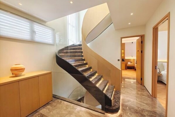 A modern spiral staircase with glass railings, leading to a well-lit room with a wooden floor. - Grand New Century Resort Dongtou Wenzhou (Wenzhou)
