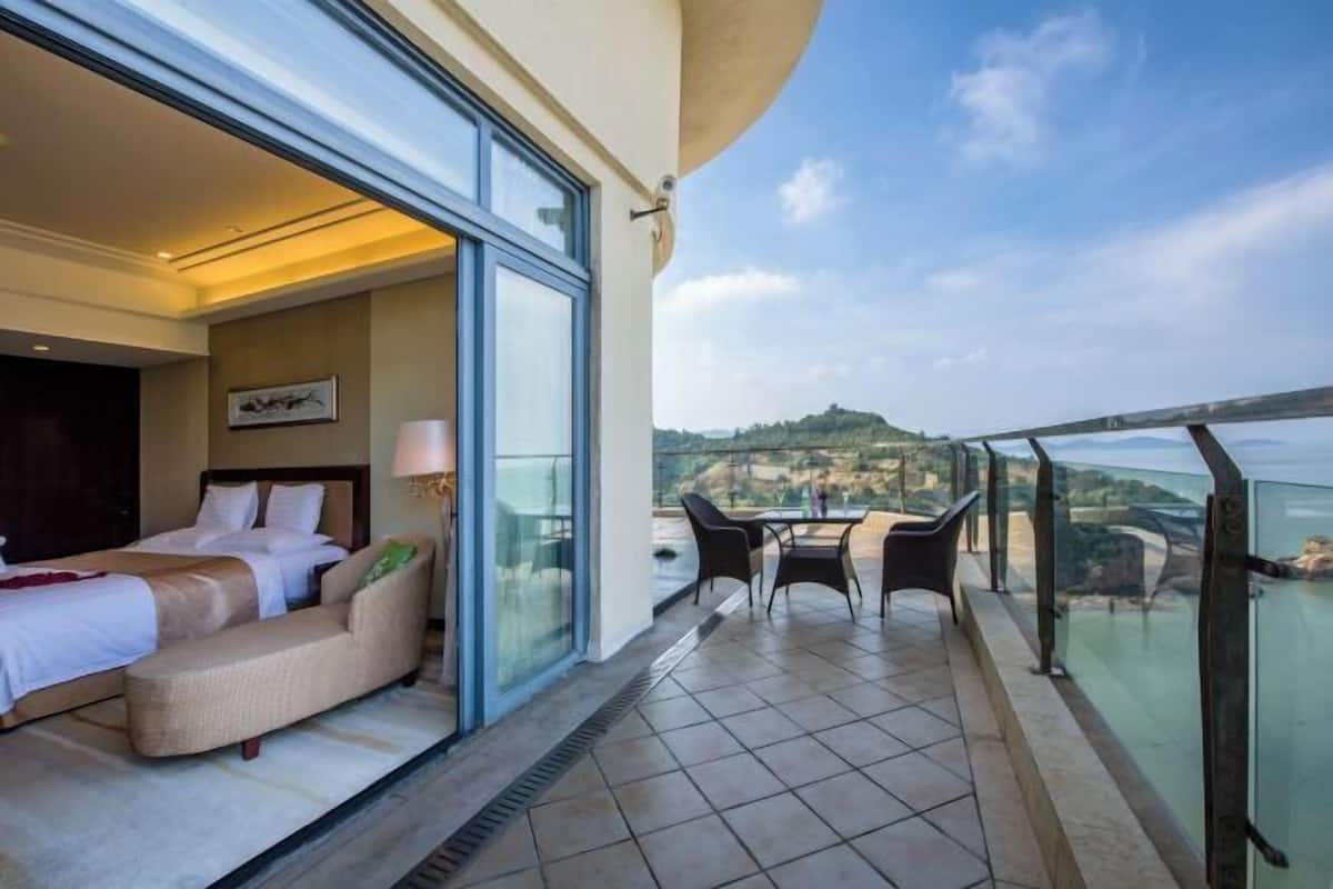 A balcony with a bed, a sofa, and a table with chairs.