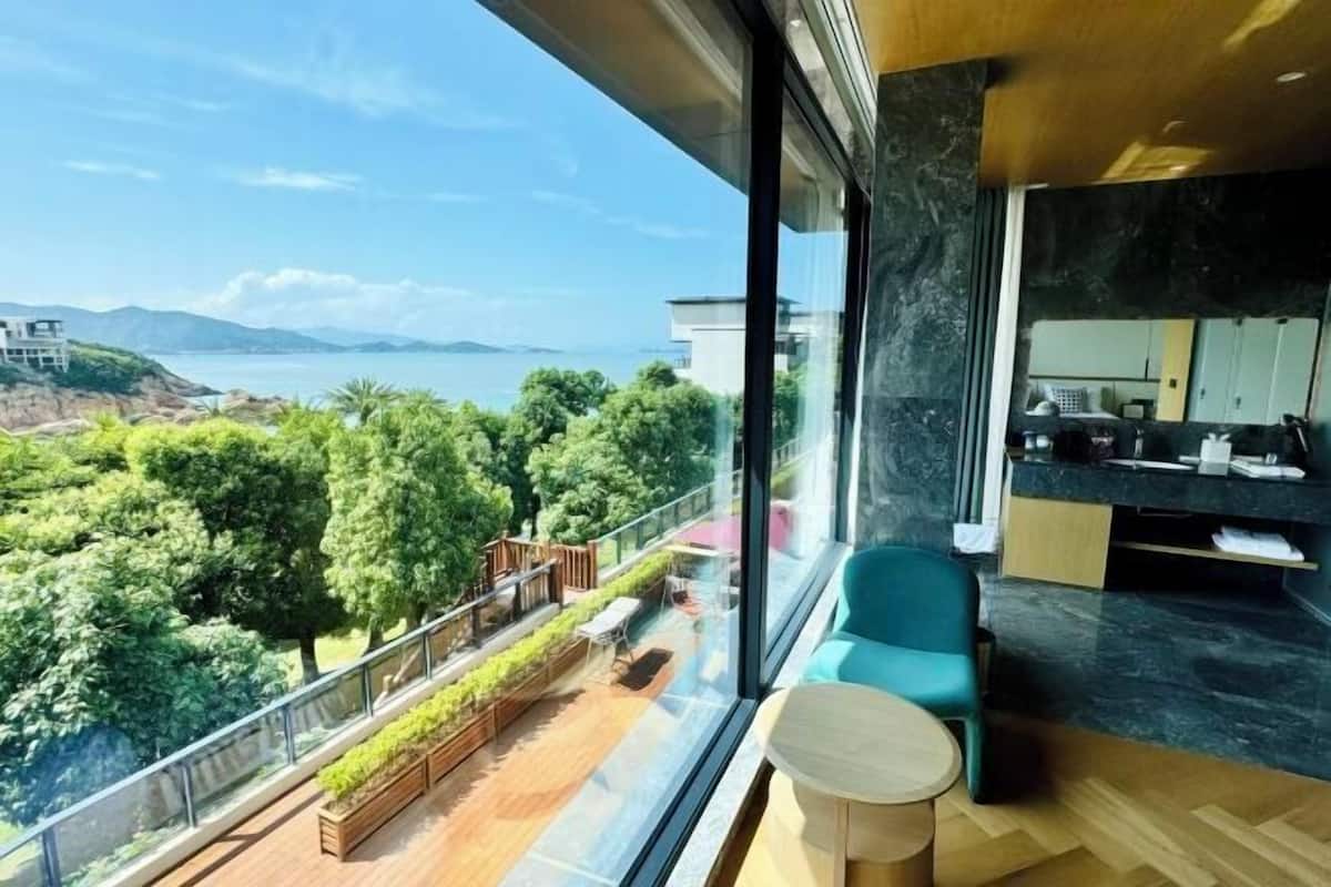 A modern room with a large window offering a view of a lush green landscape and a body of water.