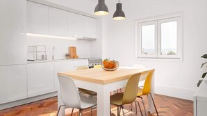 A modern kitchen with white cabinets, a wooden dining table, and two pendant lights. - 2 Classic Apartments by HostWise (Porto)