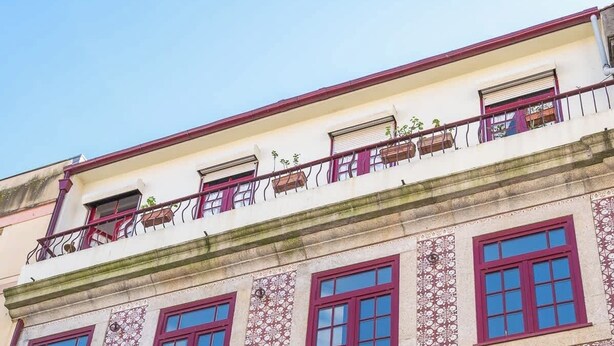 A multi-story building with a patterned facade and red-framed windows.