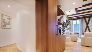 Un salon moderne avec un mur d’accent en bois, un canapé, une table basse et une grande fenêtre avec des rideaux.