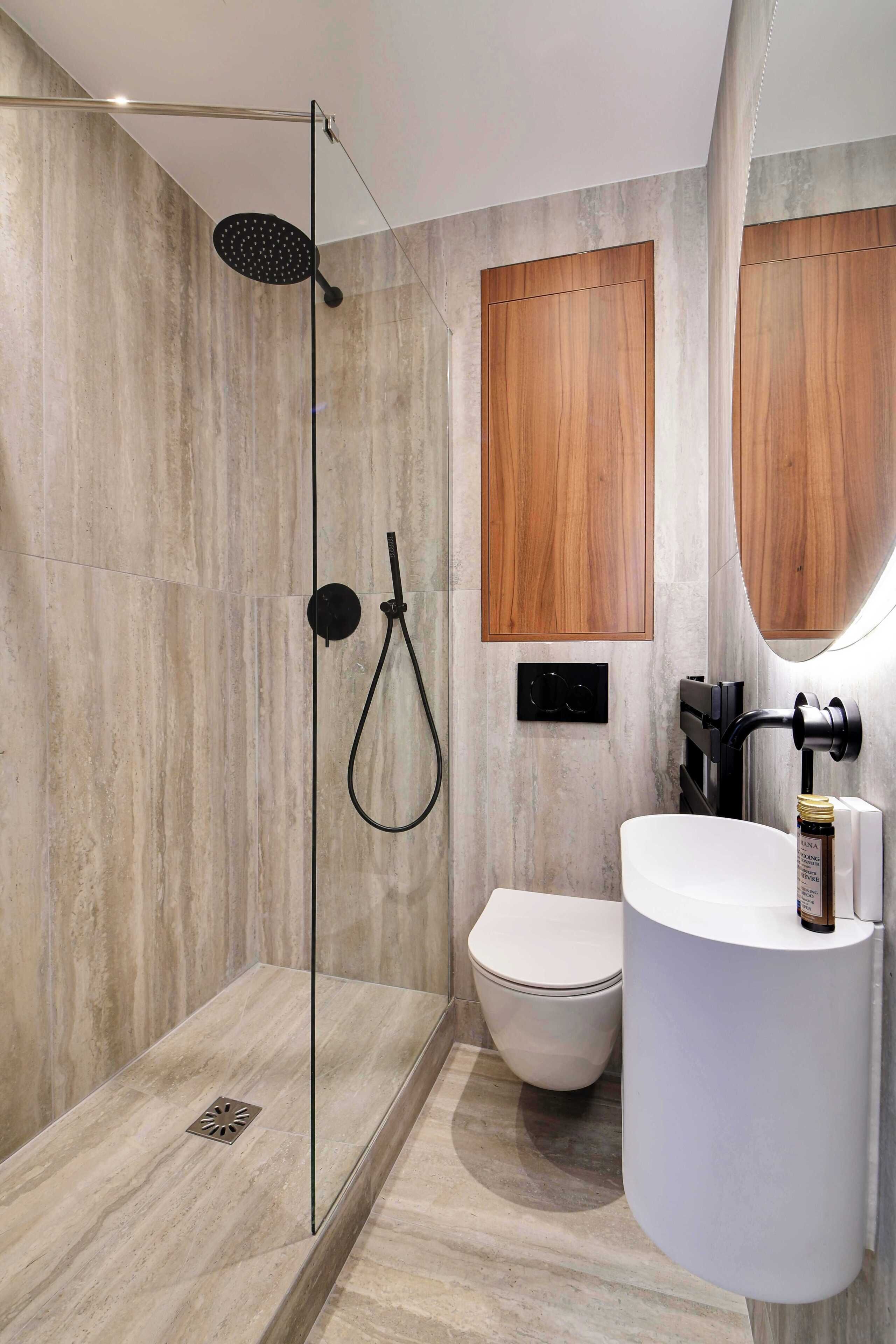 A modern bathroom with a glass-enclosed shower, a toilet, and a sink with a mirror.